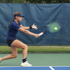 NMBA junior tennis player hitting backhand slice wide shot North Miami Beach Academy