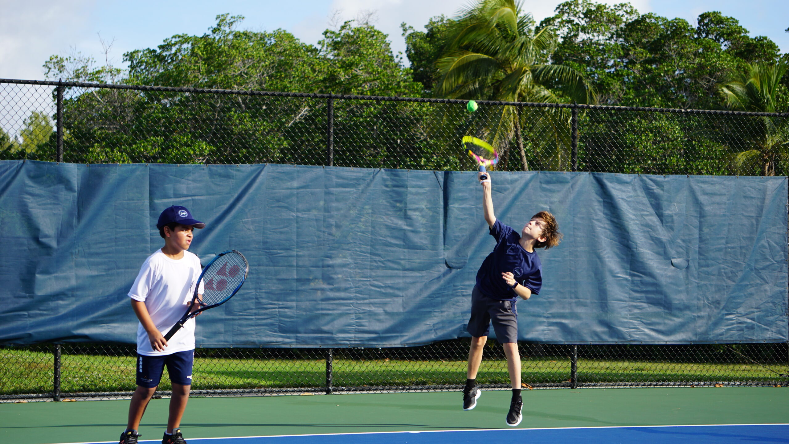 NMBA student-athlete receiving professional tennis coaching during training session at Judge Arthur Snyder Tennis Center, FIU Biscayne Bay Campus