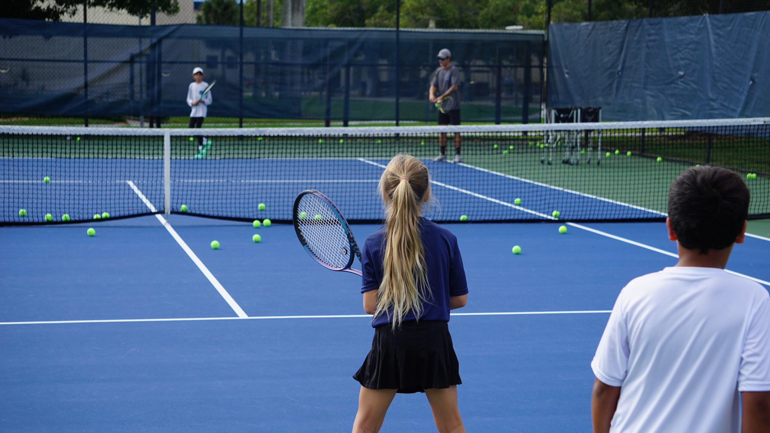 Junior tennis players competing and training at NMBA Spring Tennis Camp during spring break in North Miami Beach