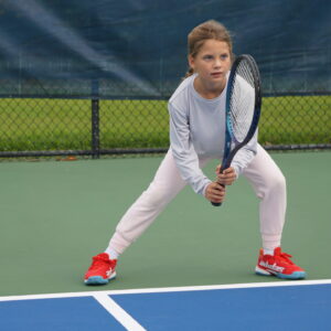 NMBA junior tennis player hitting volley on blue court North Miami Beach Academy