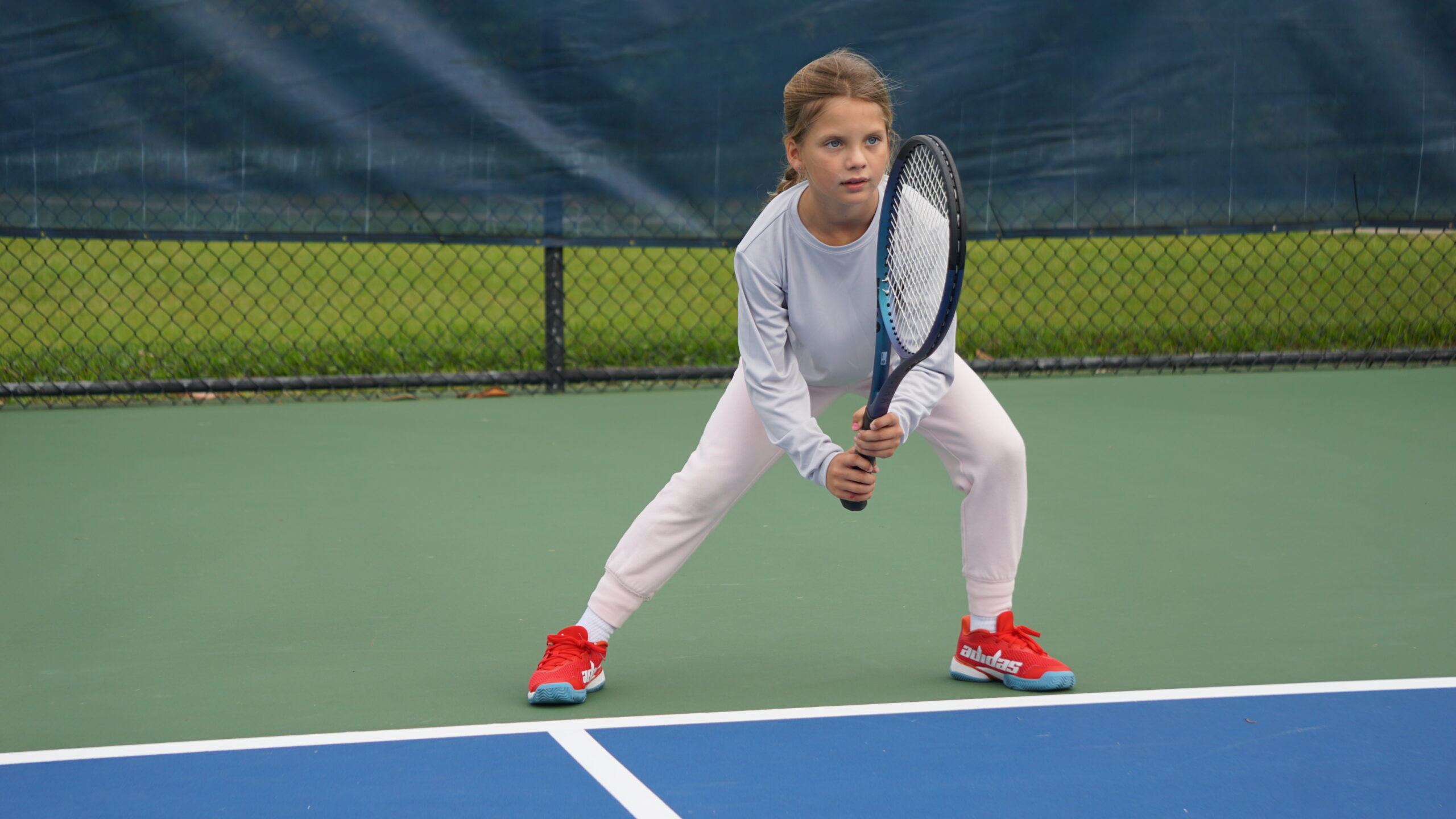 NMBA junior tennis player hitting volley on blue court North Miami Beach Academy